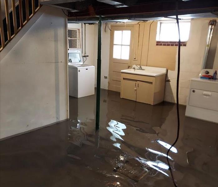 Basement with standing water with appliances and fixtures
