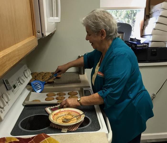 female removing cookies from a pan with a blue spatula