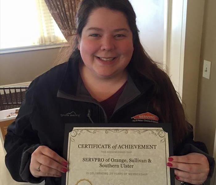 female employee holding a Certificate of Achievement