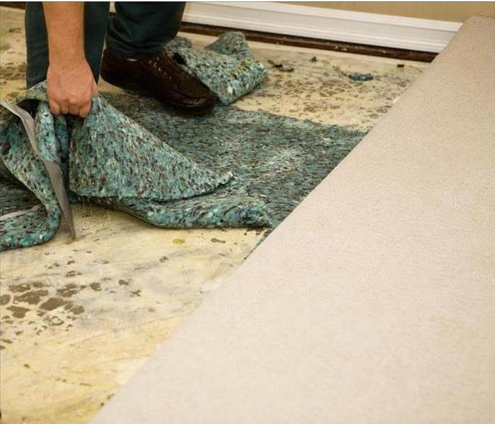 hand lifting wet carpet padding from floors